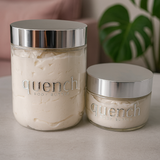 Two jars of 'quench' body butter on a surface with a plant in the background.